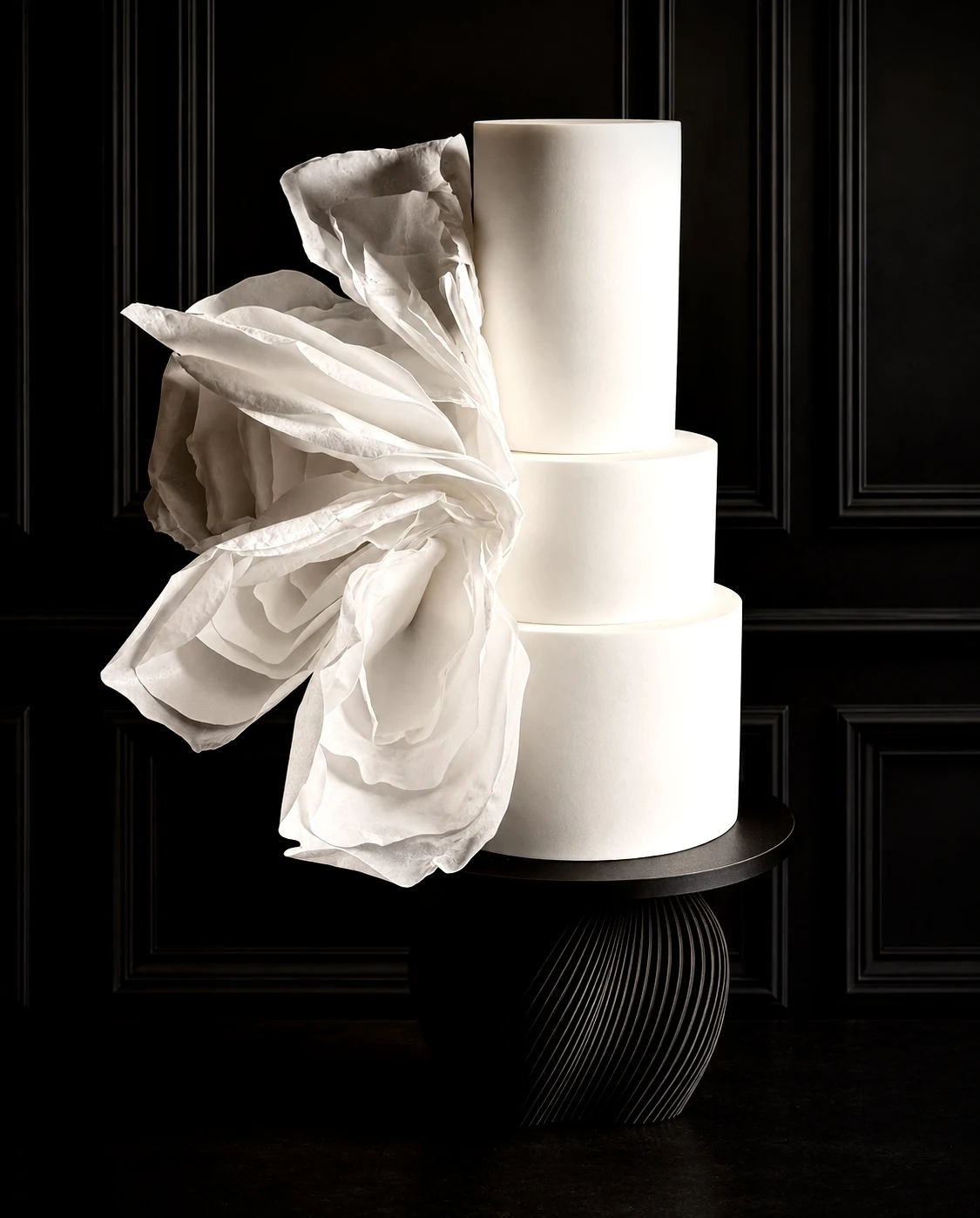 Minimalist three-tier ivory cake with oversized sculptural edible flower